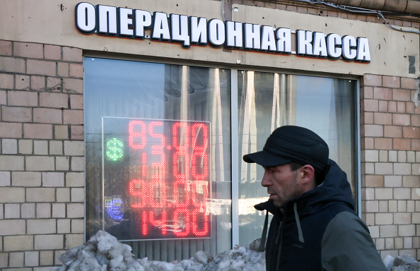 A man in Moscow passes by a display of foreign exchange rates [Anton Novoderezhkin/Getty Images]